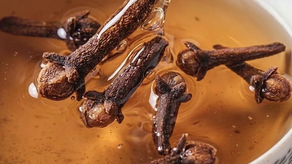 Primo piano di chiodi di garofano immersi in un infuso ambrato